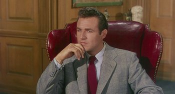 Movie still from “This Island Earth” (1955), directed by Joseph M. Newman – A man in a suit and red tie sitting in a chair; Close Up shot, Low angle