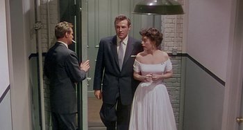 Movie still from “This Island Earth” (1955), directed by Joseph M. Newman – A man and a woman standing next to each other in front of another man; Medium shot, Over the shoulder angle
