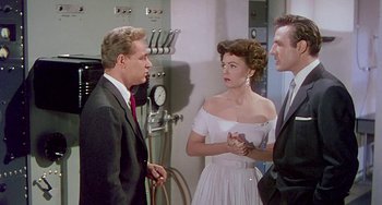 Movie still from “This Island Earth” (1955), directed by Joseph M. Newman – Two men and a woman talking to each other in a room; Medium shot, Over the shoulder angle
