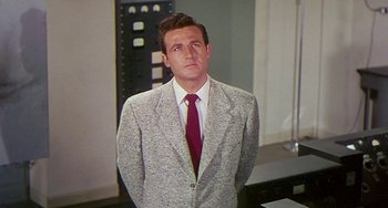 Movie still from “This Island Earth” (1955), directed by Joseph M. Newman – A man wearing a suit and tie standing in a room; Medium shot, Low angle