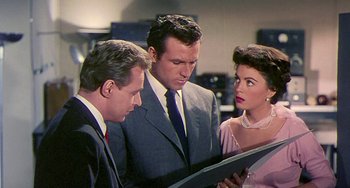 Movie still from “This Island Earth” (1955), directed by Joseph M. Newman – A man and two women looking at a piece of paper; Medium shot, Over the shoulder angle