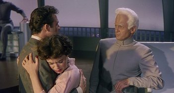 Movie still from “This Island Earth” (1955), directed by Joseph M. Newman – A man and a woman hugging next to another man; Medium shot, Over the shoulder angle