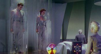 Movie still from “This Island Earth” (1955), directed by Joseph M. Newman – A woman standing next to a man in a room; Wide shot, Low angle