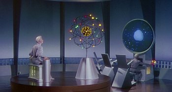 Movie still from “This Island Earth” (1955), directed by Joseph M. Newman – A woman sitting on a chair next to a table; Wide shot, Low angle