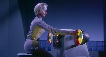 Movie still from “This Island Earth” (1955), directed by Joseph M. Newman – A woman in a helmet sitting on a steering wheel of a boat; Medium shot, Low angle