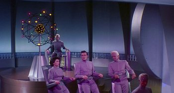 Movie still from “This Island Earth” (1955), directed by Joseph M. Newman – A group of people sitting on a chair in a room; Wide shot, Low angle