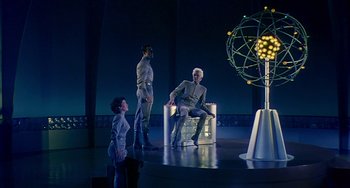 Movie still from “This Island Earth” (1955), directed by Joseph M. Newman – Two men and a boy are sitting on a stage; Wide shot, Low angle