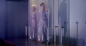Movie still from “This Island Earth” (1955), directed by Joseph M. Newman – A man standing in front of another man in front of a mirror; Wide shot, Low angle