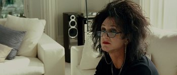 Movie still from “This Must Be the Place” (2011), directed by Paolo Sorrentino – A woman sitting on a white couch wearing glasses; Close Up shot, Low angle