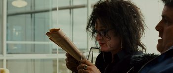Movie still from “This Must Be the Place” (2011), directed by Paolo Sorrentino – A woman reading a newspaper while holding a glass of wine; Close Up shot, Over the shoulder angle