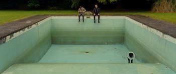 Movie still from “This Must Be the Place” (2011), directed by Paolo Sorrentino – Two men sitting in a swimming pool with their feet in the water; Extreme Wide shot, High angle