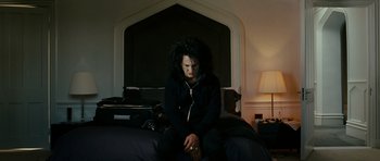 Movie still from “This Must Be the Place” (2011), directed by Paolo Sorrentino – A man sitting on a bed with a black jacket on; Medium shot, Low angle