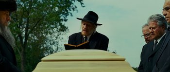Movie still from “This Must Be the Place” (2011), directed by Paolo Sorrentino – An old man wearing a hat and reading a book; Medium shot, Low angle