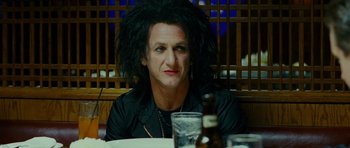 Movie still from “This Must Be the Place” (2011), directed by Paolo Sorrentino – A man sitting at a table with a bottle of beer in front of him; Close Up shot, Over the shoulder angle