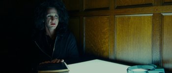 Movie still from “This Must Be the Place” (2011), directed by Paolo Sorrentino – A person sitting at a table with a laptop; Medium shot, Low angle