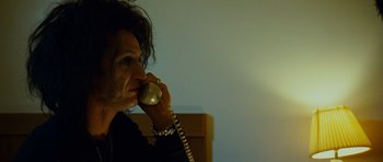 Movie still from “This Must Be the Place” (2011), directed by Paolo Sorrentino – A person talking on a phone in a room; Close Up shot, Low angle