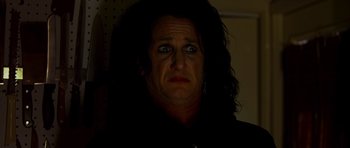 Movie still from “This Must Be the Place” (2011), directed by Paolo Sorrentino – A man with long black hair and blue eyes stares at the camera; Close Up shot, Low angle