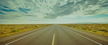 Movie still from “This Must Be the Place” (2011), directed by Paolo Sorrentino – An empty road with a cloudy sky in the background; Extreme Wide shot, High angle
