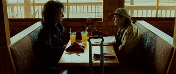 Movie still from “This Must Be the Place” (2011), directed by Paolo Sorrentino – A man and a woman sitting at a table with orange juice; Medium shot, Over the shoulder angle