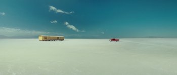 Movie still from “This Must Be the Place” (2011), directed by Paolo Sorrentino – A red truck and a white truck in the middle of the desert; Extreme Wide shot, High angle