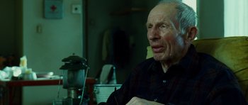 Movie still from “This Must Be the Place” (2011), directed by Paolo Sorrentino – An older man sitting at a table in front of a coffee pot; Close Up shot, Low angle