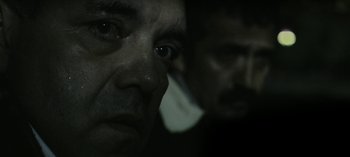 Movie still from “Three Monkeys” (2008), directed by Nuri Bilge Ceylan – Two men are looking into the camera with their eyes wide open; Extreme Close Up shot, Over the shoulder angle