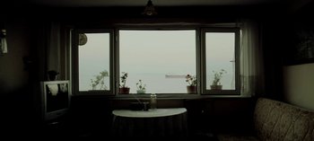 Movie still from “Three Monkeys” (2008), directed by Nuri Bilge Ceylan – A room with a table and a window with a view of the ocean; Extreme Wide shot, Low angle