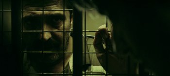 Movie still from “Three Monkeys” (2008), directed by Nuri Bilge Ceylan – A man looking through the bars of a jail cell; Close Up shot, Over the shoulder angle