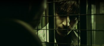 Movie still from “Three Monkeys” (2008), directed by Nuri Bilge Ceylan – A man with a beard is behind a fence; Extreme Close Up shot, Over the shoulder angle