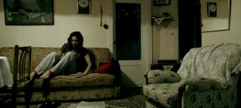 Movie still from “Three Monkeys” (2008), directed by Nuri Bilge Ceylan – A woman sitting on a couch in a living room; Wide shot, High angle