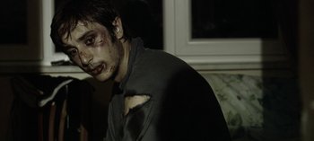 Movie still from “Three Monkeys” (2008), directed by Nuri Bilge Ceylan – A young man with a bruised face is posing for a picture; Close Up shot, Over the shoulder angle