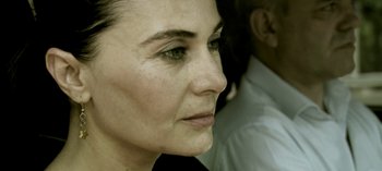 Movie still from “Three Monkeys” (2008), directed by Nuri Bilge Ceylan – A woman's face with a man in the background; Close Up shot, Over the shoulder angle