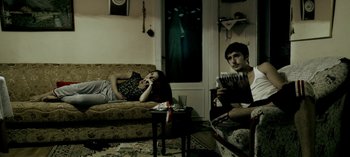 Movie still from “Three Monkeys” (2008), directed by Nuri Bilge Ceylan – A man and a woman sitting in a living room; Wide shot, High angle