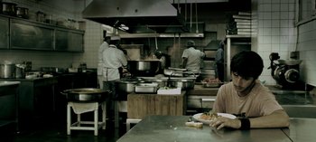 Movie still from “Three Monkeys” (2008), directed by Nuri Bilge Ceylan – A group of people working in a restaurant kitchen preparing food; Medium shot, High angle