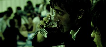 Movie still from “Three Monkeys” (2008), directed by Nuri Bilge Ceylan – A man drinking a glass of wine at a party; Extreme Close Up shot, High angle