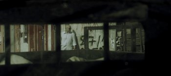 Movie still from “Three Monkeys” (2008), directed by Nuri Bilge Ceylan – A man standing in front of a window looking at himself; Medium shot, Low angle