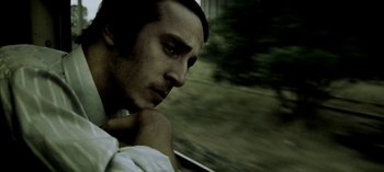 Movie still from “Three Monkeys” (2008), directed by Nuri Bilge Ceylan – A man with a hat is looking out a window; Close Up shot, Low angle