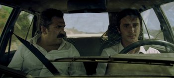 Movie still from “Three Monkeys” (2008), directed by Nuri Bilge Ceylan – Two men in the back seat of a car looking at each other; Medium shot, Low angle