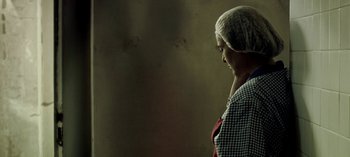 Movie still from “Three Monkeys” (2008), directed by Nuri Bilge Ceylan – A woman wearing a headscarf is standing in a dark room; Close Up shot, Low angle