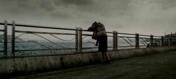 Movie still from “Three Monkeys” (2008), directed by Nuri Bilge Ceylan – A woman standing on a bridge looking at the ocean; Extreme Wide shot, High angle