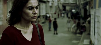 Movie still from “Three Monkeys” (2008), directed by Nuri Bilge Ceylan – A woman in a red shirt is walking down the street; Close Up shot, Low angle