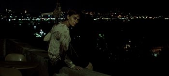 Movie still from “Three Monkeys” (2008), directed by Nuri Bilge Ceylan – A woman sitting on top of a building at night; Medium shot, Overhead angle