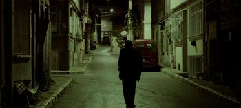 Movie still from “Three Monkeys” (2008), directed by Nuri Bilge Ceylan – A person walking down a street at night; Wide shot, Low angle