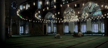 Movie still from “Three Monkeys” (2008), directed by Nuri Bilge Ceylan – A man kneeling on the ground in a mosque; Extreme Wide shot, High angle