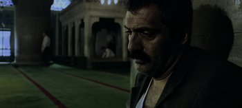 Movie still from “Three Monkeys” (2008), directed by Nuri Bilge Ceylan – A person wearing a suit; Close Up shot, Low angle