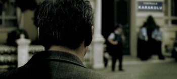 Movie still from “Three Monkeys” (2008), directed by Nuri Bilge Ceylan – A man's face as he stands in front of a building; Extreme Close Up shot, Over the shoulder angle