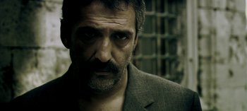 Movie still from “Three Monkeys” (2008), directed by Nuri Bilge Ceylan – A person wearing a suit; Close Up shot, Low angle