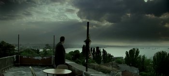 Movie still from “Three Monkeys” (2008), directed by Nuri Bilge Ceylan – A man standing on top of a building near a lake; Extreme Wide shot, Low angle
