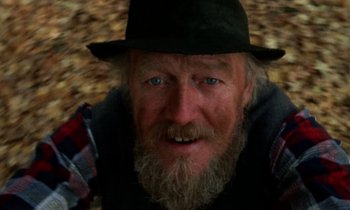 An old man with a beard wearing a black hat