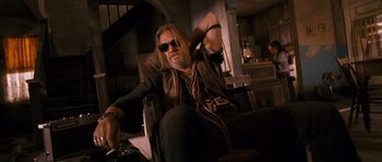 Movie still from “Tideland” (2005), directed by Terry Gilliam – A man sitting in a chair wearing sunglasses; Medium shot, Low angle
